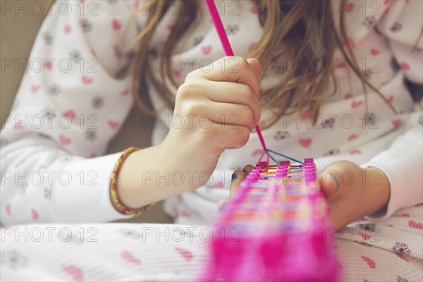 Caucasian girl knitting with rainbow loom