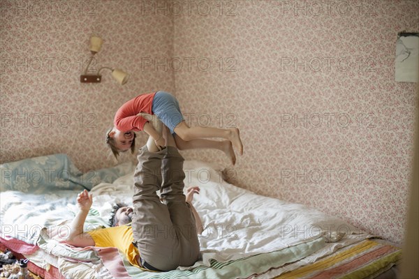 Caucasian father and daughter playing on bed