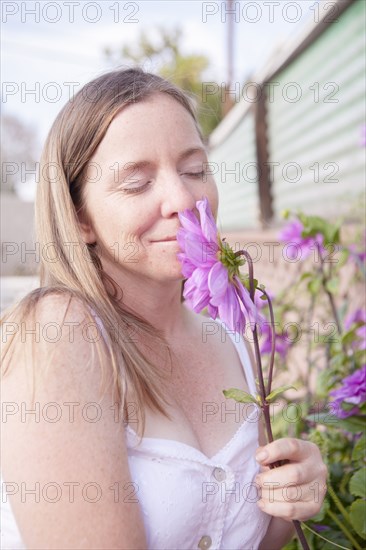 Mixed race woman smelling flowers in garden