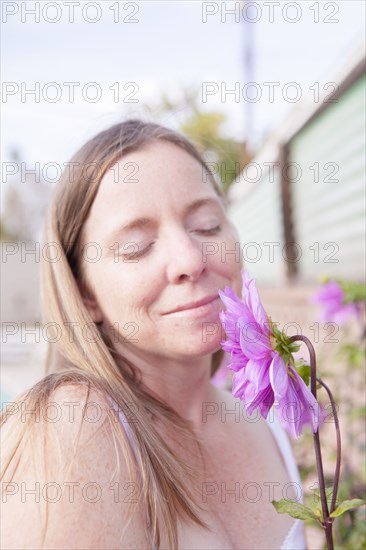 Mixed race woman smelling flowers in garden