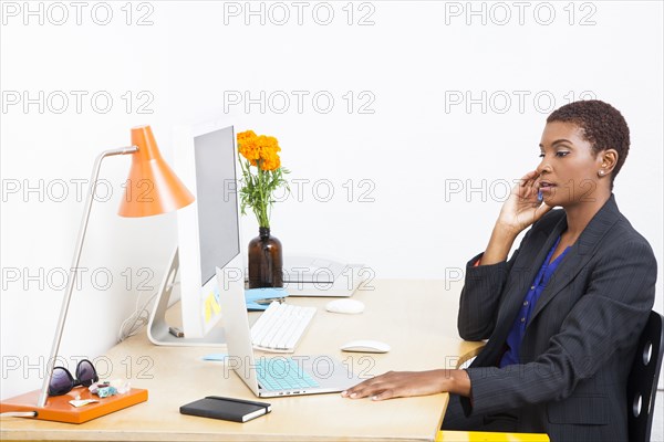 Black businesswoman talking on cell phone at office desk