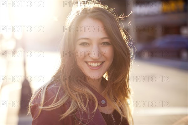 Woman smiling on sunny city sidewalk