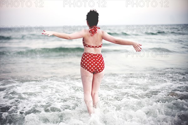 Caucasian teenage girl splashing in ocean waves