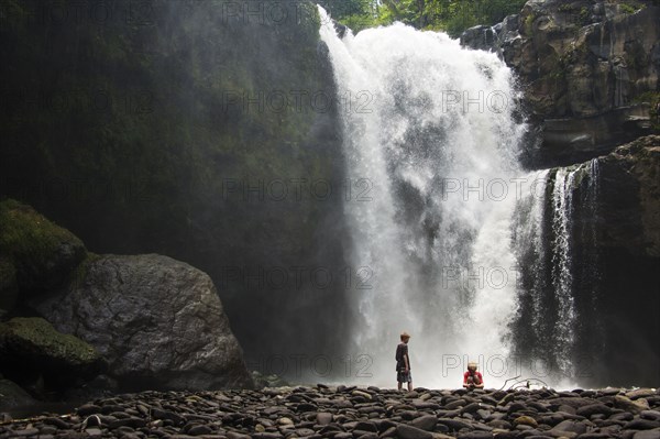 Caucasian tourists admiring waterfall in jungle