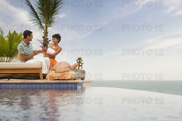 Hispanic couple relaxing near swimming pool