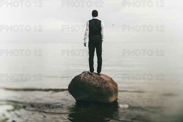 Caucasian man standing on rock at beach