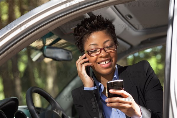 Black woman in vehicle using two cell phones