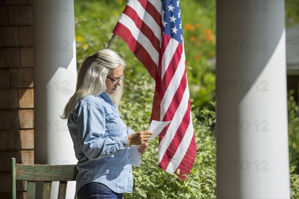 Caucasian woman reading letter on porch