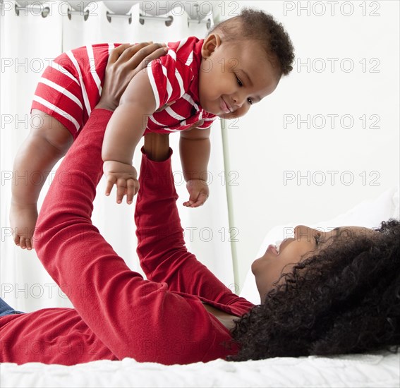 African American woman lifting baby son into the air