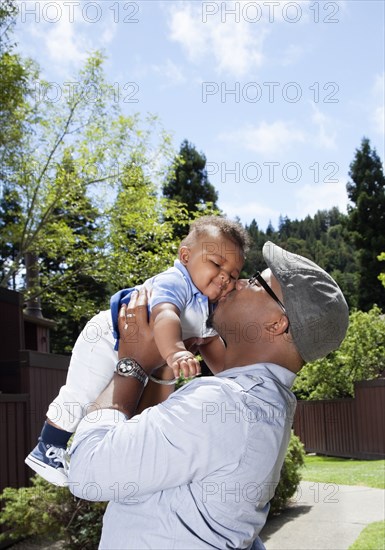 African American father lifting and kissing baby son