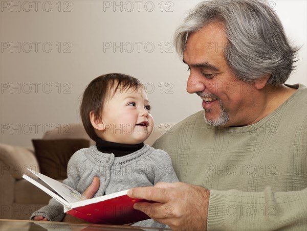 Grandfather reading book to granddaughter