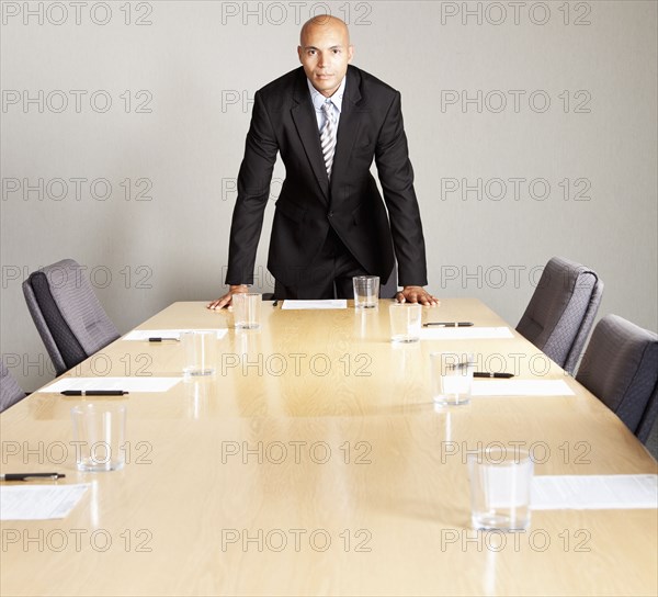 Mixed race businessman leaning on conference room table