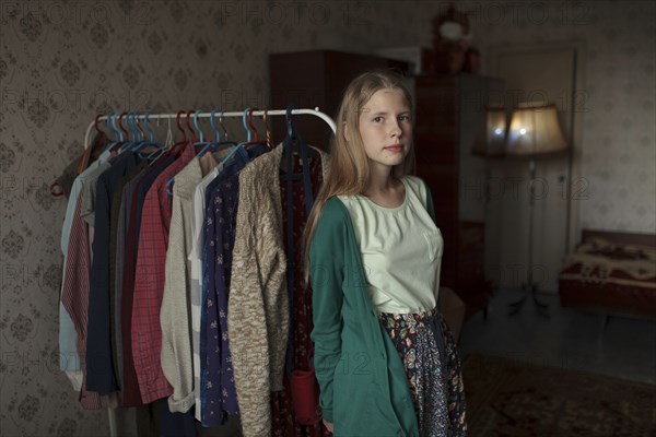 Portrait of pensive Caucasian woman leaning on clothing rack