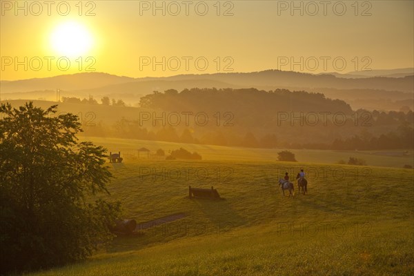 People horseback riding at sunset