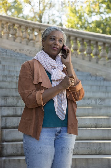 Black woman on stone staircase talking on cell phone