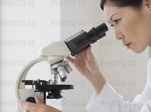 Asian female scientist looking into microscope