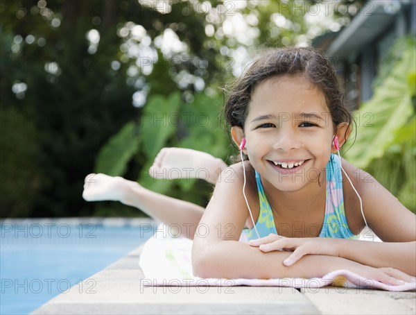 Hispanic girl listening to music at poolside