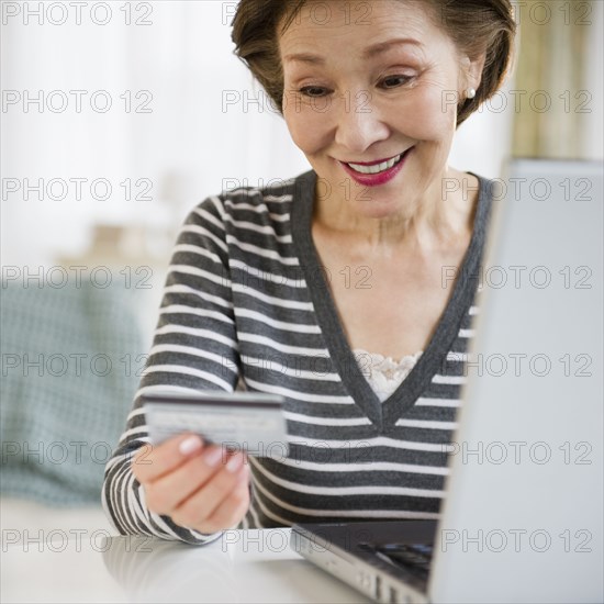 Japanese woman holding credit card using laptop