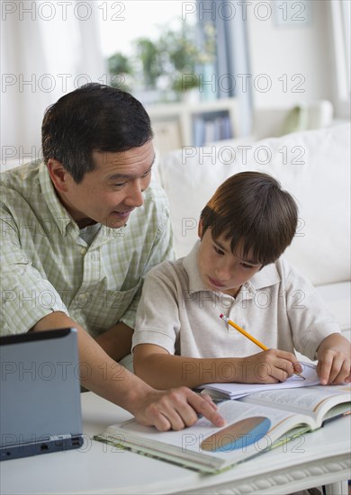 Father helping son with homework in living room