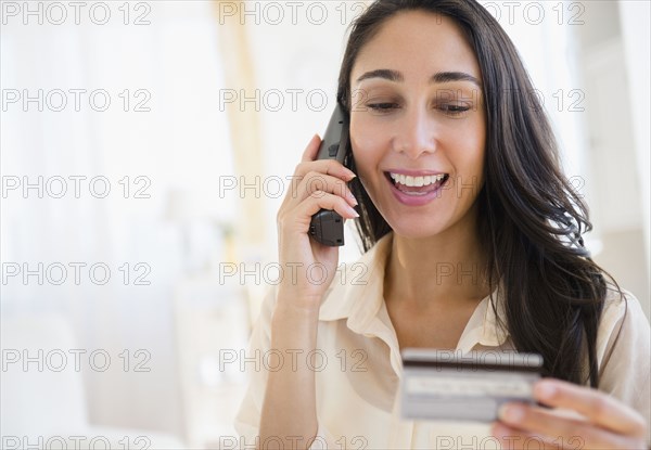 Caucasian woman using credit card on telephone