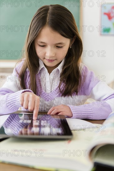 Mixed race girl using tablet computer in class