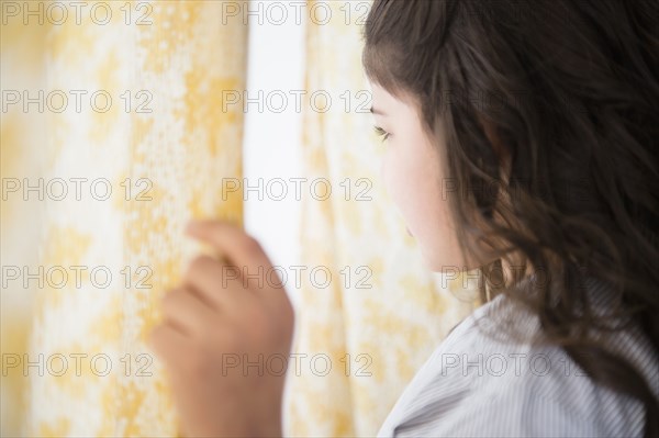 Hispanic girl looking out window