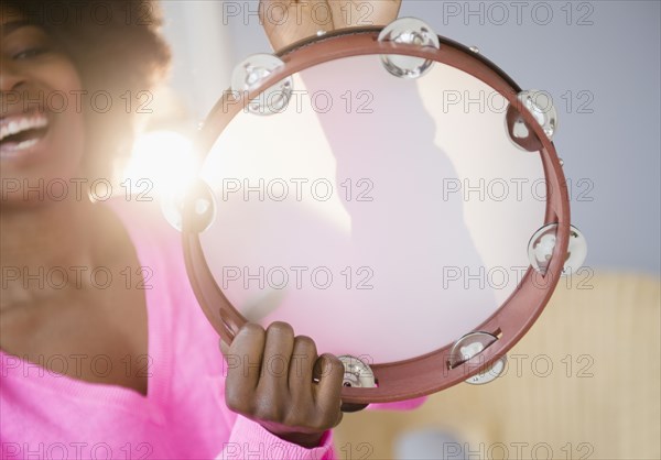 Mixed race woman playing tambourine