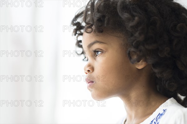 Close up of pensive African American girl looking out window
