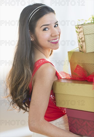 Portrait of smiling Hispanic woman carrying Christmas gifts