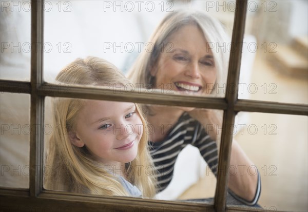 Senior Caucasian woman and granddaughter looking out window