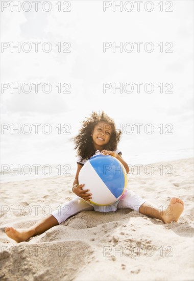 Mixed race girl playing with ball on beach