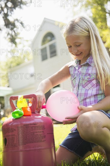 Caucasian girl filling balloons outdoors
