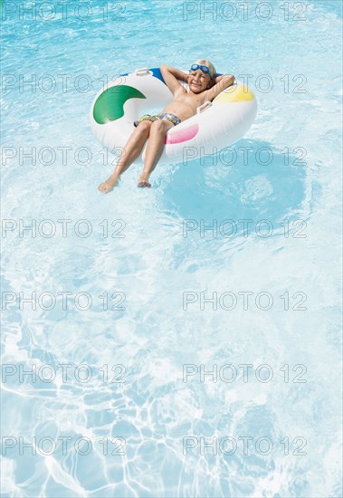 Caucasian boy floating in inflatable ring in swimming pool