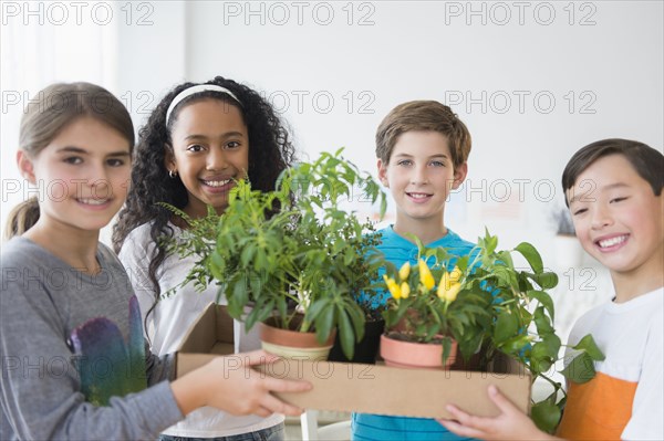 Smiling children holding potted plants