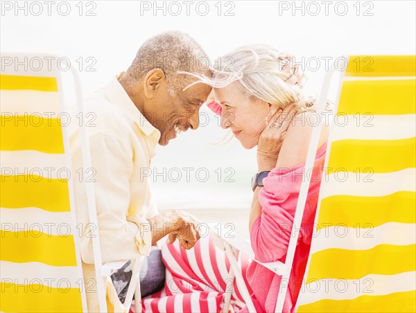 Older couple sitting in lawn chairs on beach