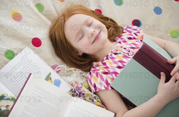 Caucasian girl reading books on bed