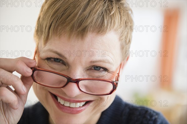 Caucasian woman peering over eyeglasses