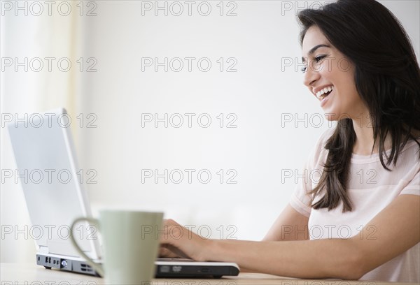 Woman using laptop with cup of coffee