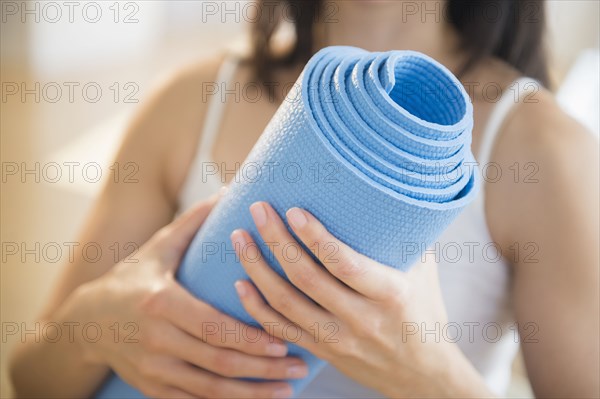 Mixed race woman holding exercise mat