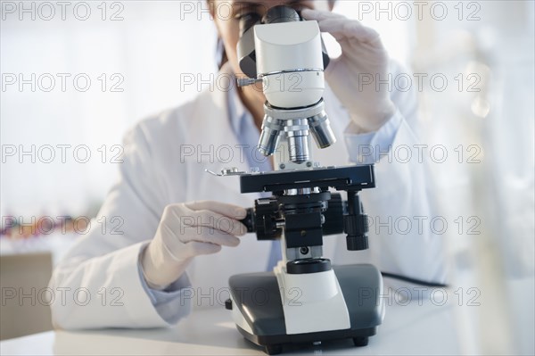 Mixed race scientist using microscope in laboratory