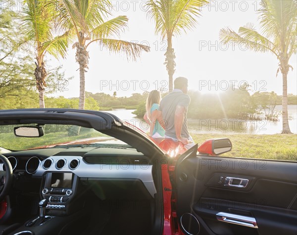 Caucasian couple walking near convertible