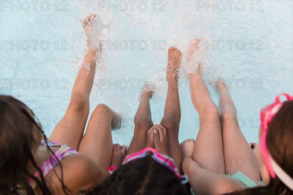 Girls splashing feet in swimming pool