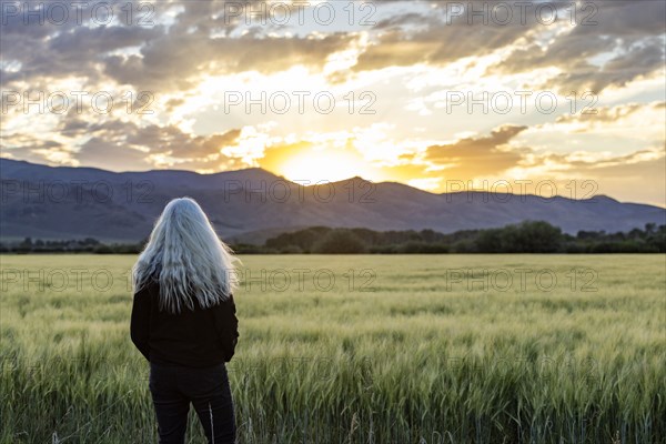 Senior woman admiring sunrise over mountains