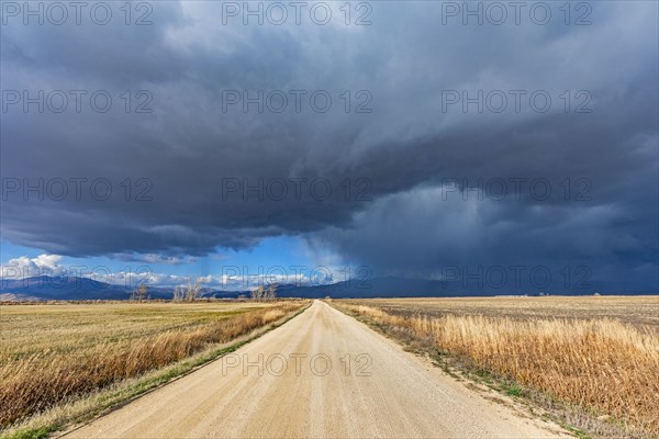 Storm clouds over empty dirt road in rural landscape, Fairfield, Idaho, USA