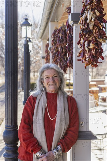 Portrait of smiling woman leaning against column at sidewalk cafe, Lamy, New Mexico, USA