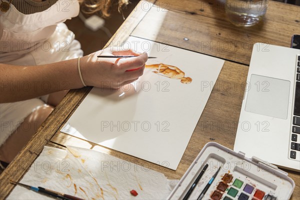 Close-up of teenage girl painting with watercolors at table, Lamy, New Mexico, USA