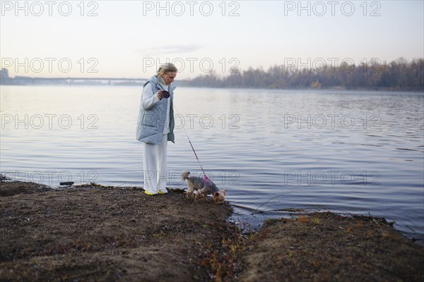 Woman with Yorkshire Terrier on lakeshore, Omsk, , Russia