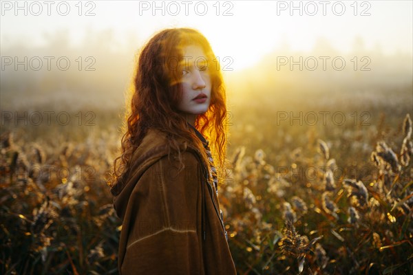 Portrait of redhead women in foggy field in autumn, Omsk, , Russia