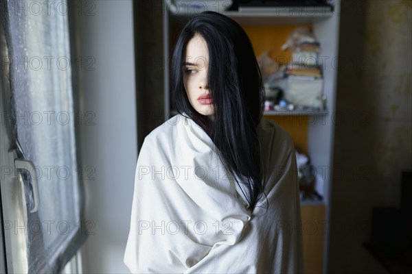 Portrait of pensive woman wrapped in white sheet, Omsk, , Russia