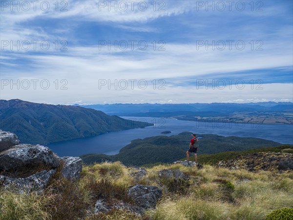 Hiker looking at fjord and mountains in Fiordland National Park, Te Anau, Fiordland, New Zealand